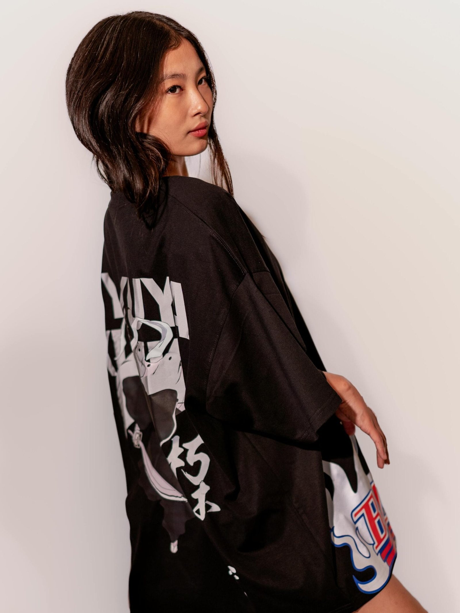 Stylish woman wearing an oversized black graphic T-shirt in a studio setting.